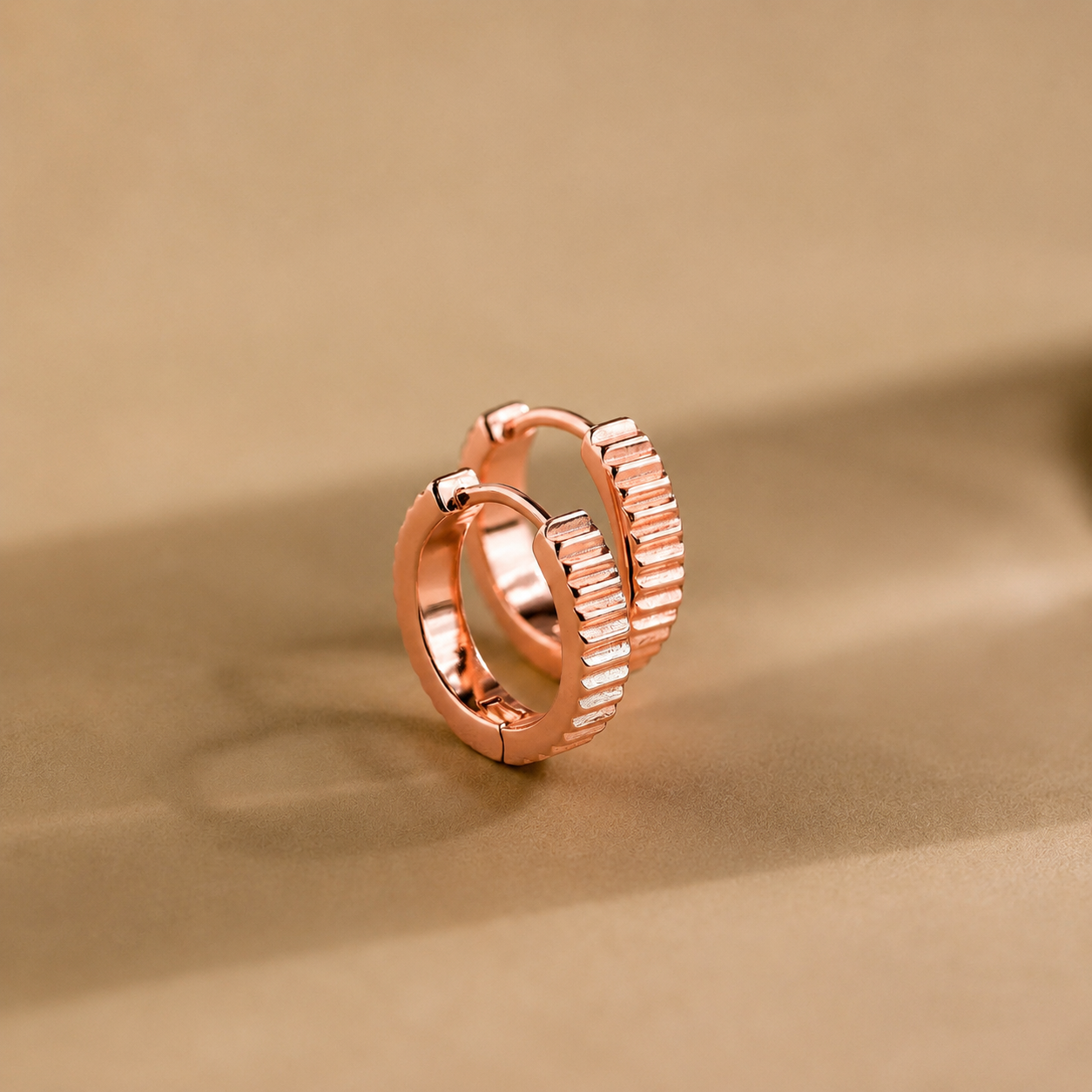 Rose gold hoop earring on a beige background